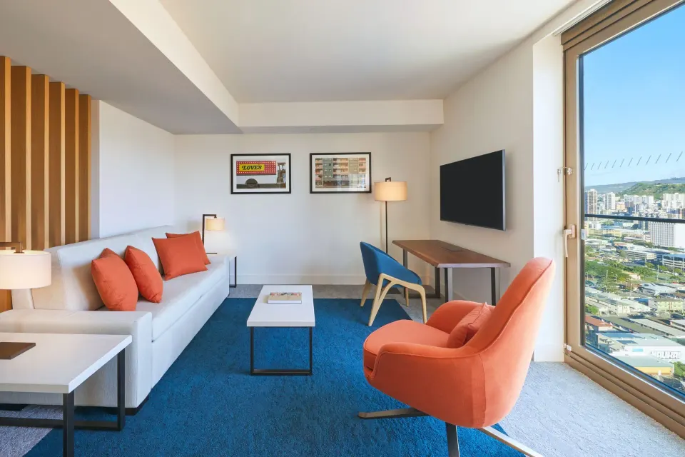 Panoramic View suite living room at Renaissance Honolulu Hotel & Spa with sofa, desk and city window.