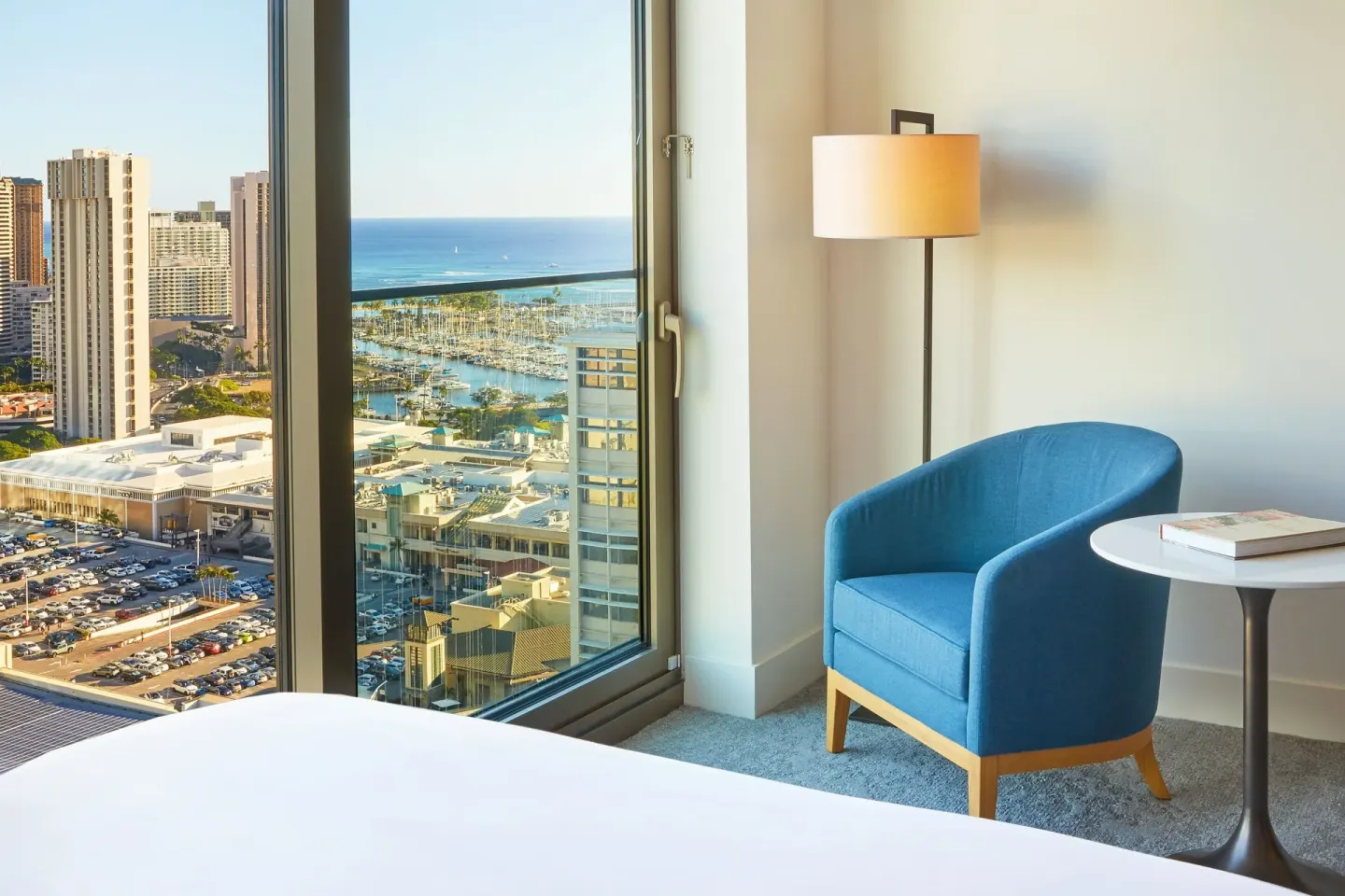 Partial ocean view suite bedroom and blue chair at Renaissance Honolulu Hotel & Spa.