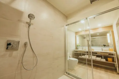 Bathroom with glass shower, vanity and toilet at Renaissance Wind Creek Aruba Resort.