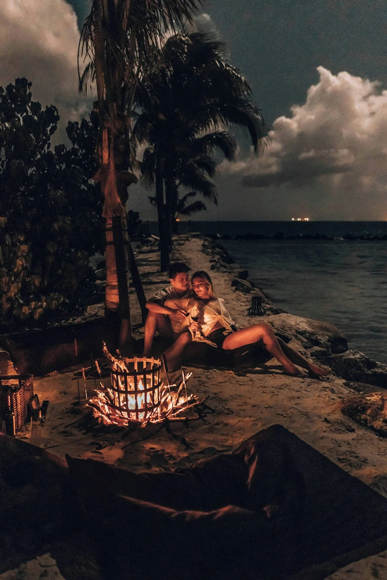 Couple by a beach fire pit at night at Renaissance Wind Creek Aruba Resort.