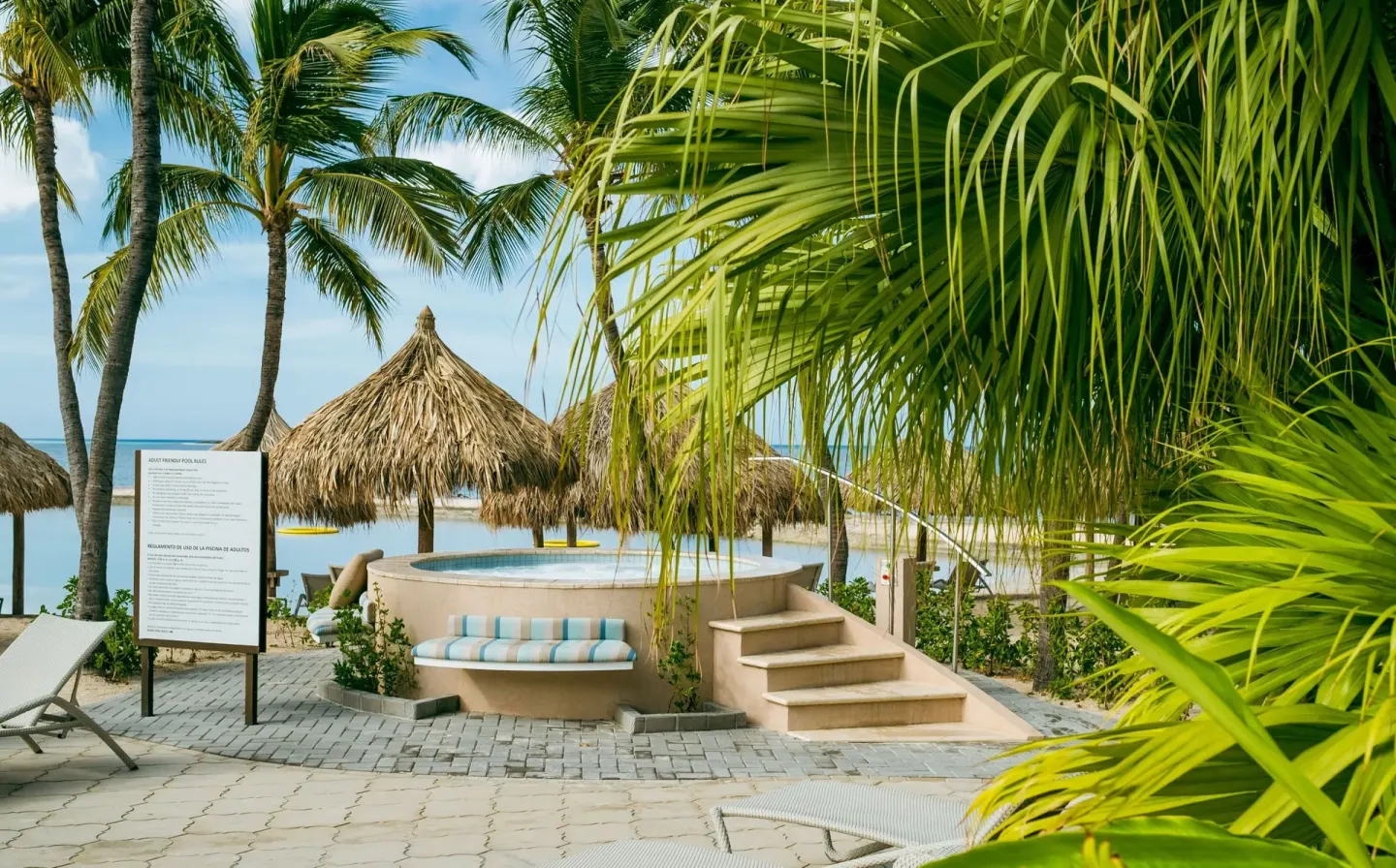 Beachside hot tub and palm trees at Renaissance Wind Creek Aruba Resort.