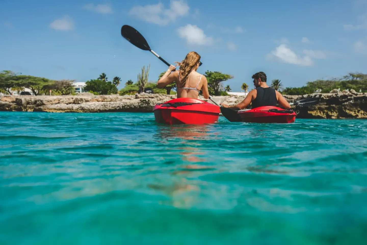 Guests kayak in turquoise water near Renaissance Wind Creek Aruba Resort.