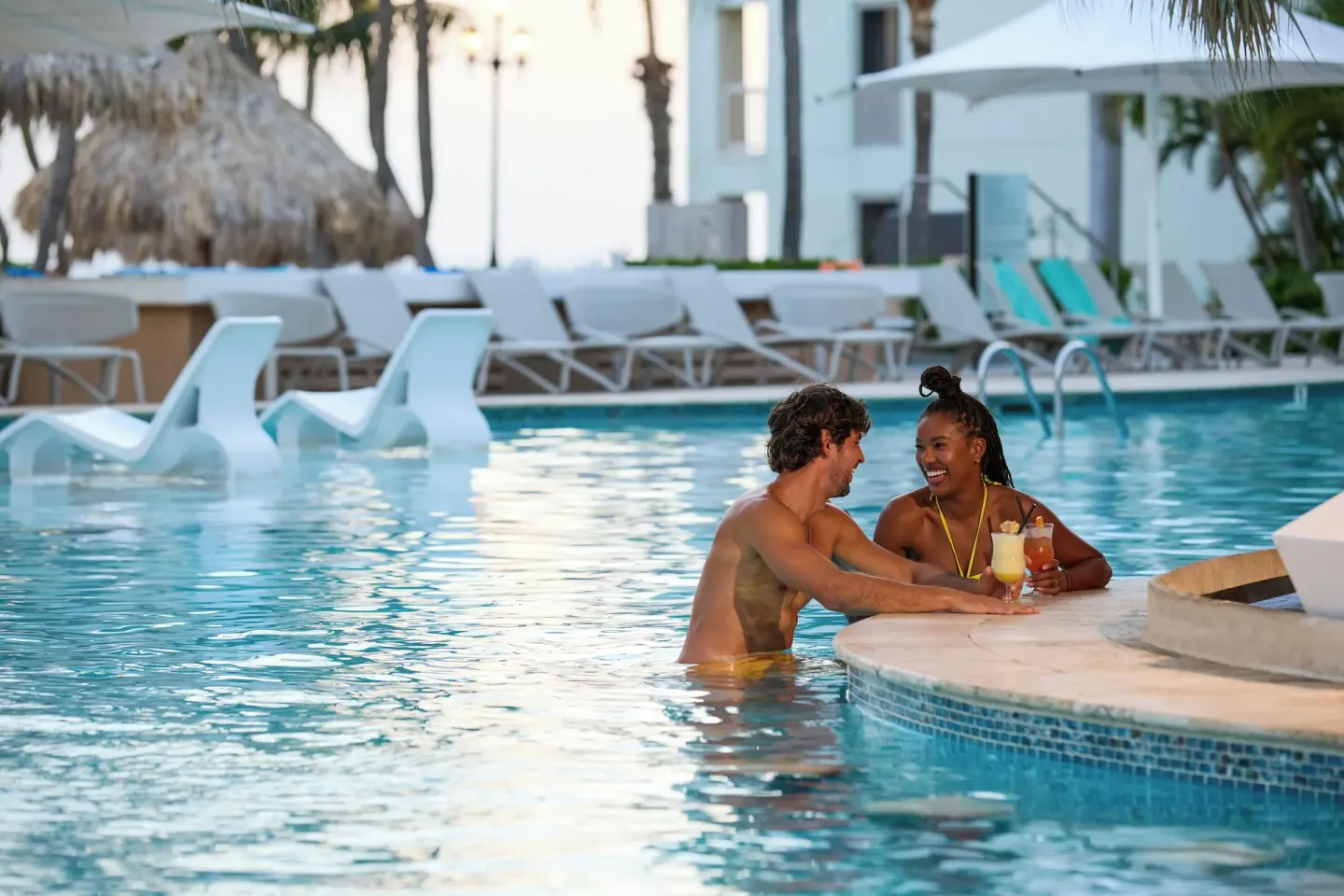 Couple with drinks in the pool at Renaissance Wind Creek Aruba Resort.