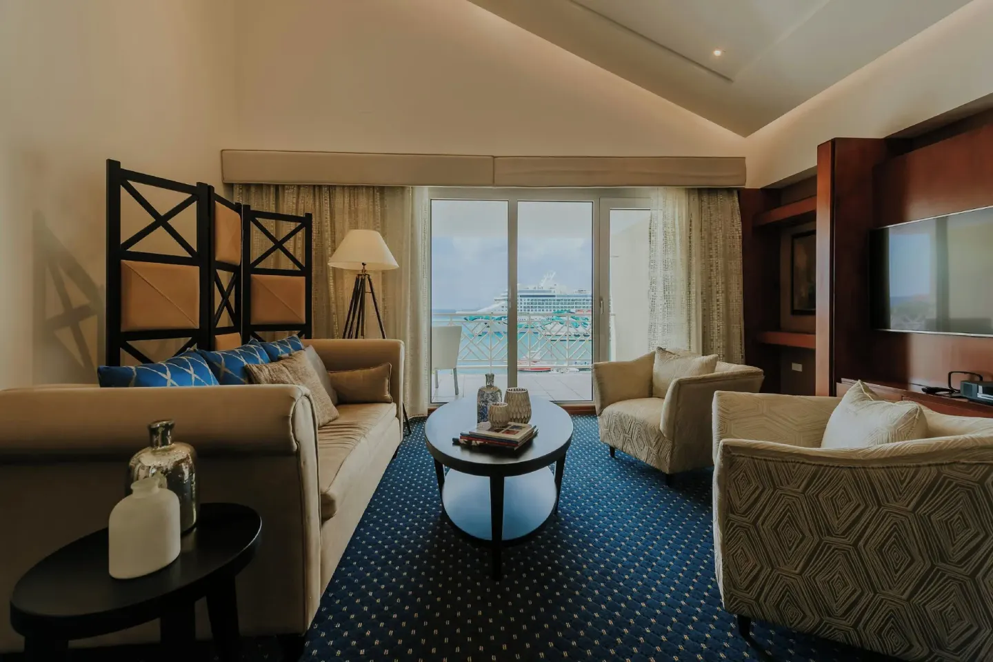 Suite living room with armchairs and balcony view at Renaissance Wind Creek Aruba Resort.