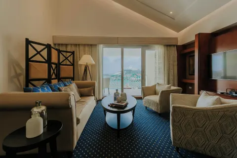 Suite living room with armchairs and balcony view at Renaissance Wind Creek Aruba Resort.