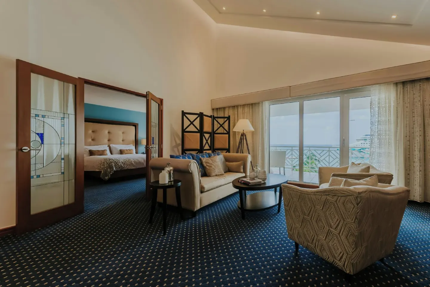 Suite living room with balcony and bedroom at Renaissance Wind Creek Aruba Resort.