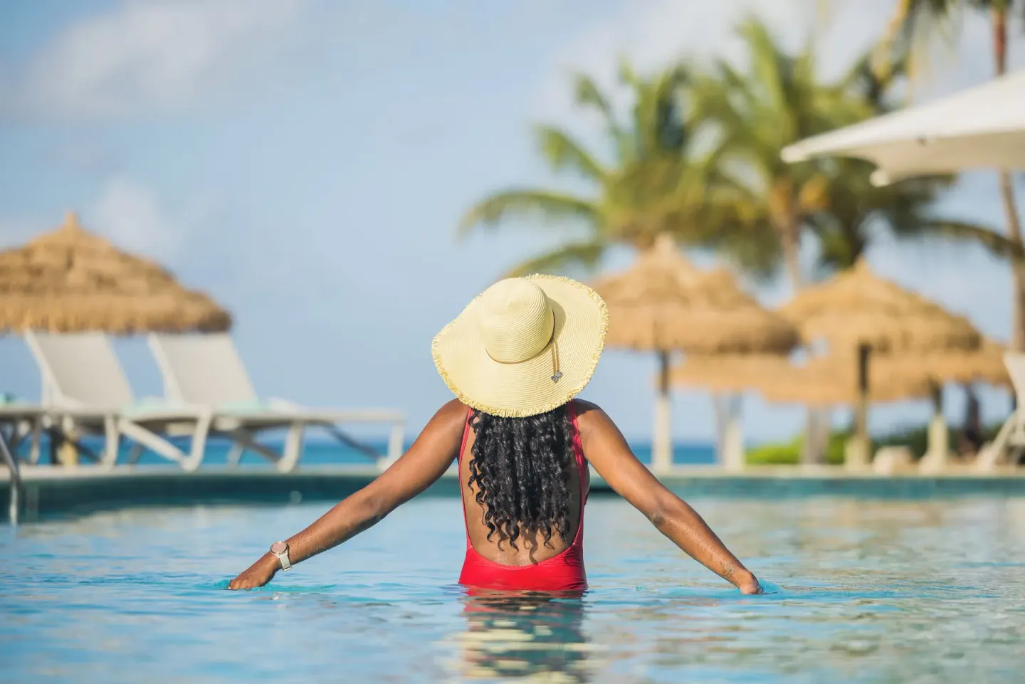 Guest in a red swimsuit standing in the pool at Renaissance Wind Creek Aruba Resort.