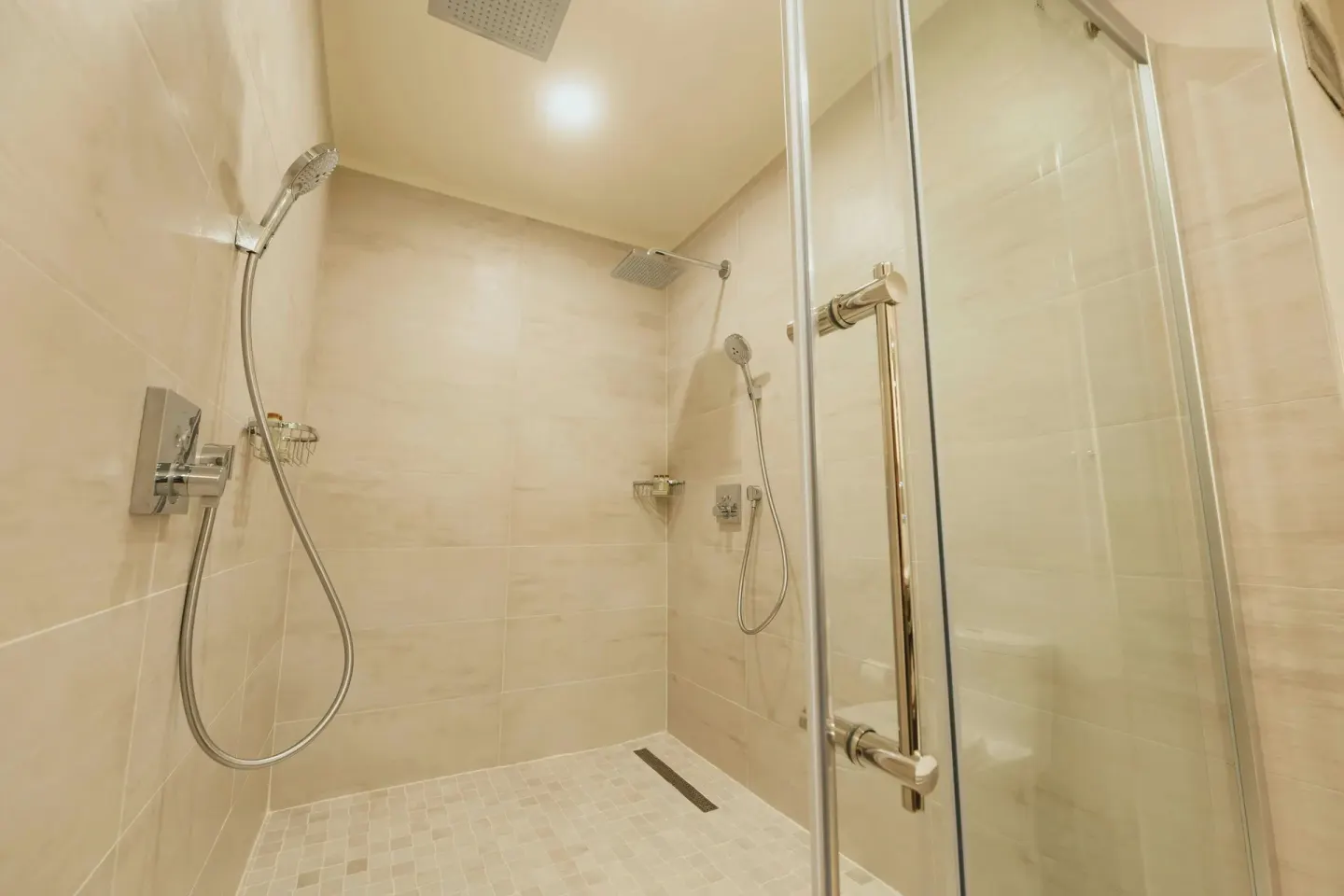 Walk-in tiled shower with handheld fixtures at Renaissance Wind Creek Aruba Resort.
