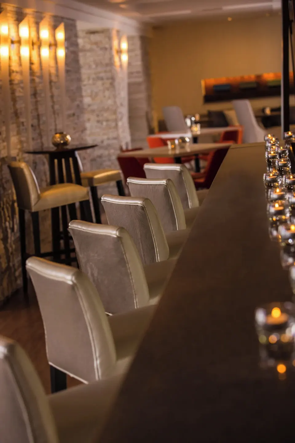 Candlelit bar counter with cream chairs at Renaissance Wind Creek Aruba Resort.
