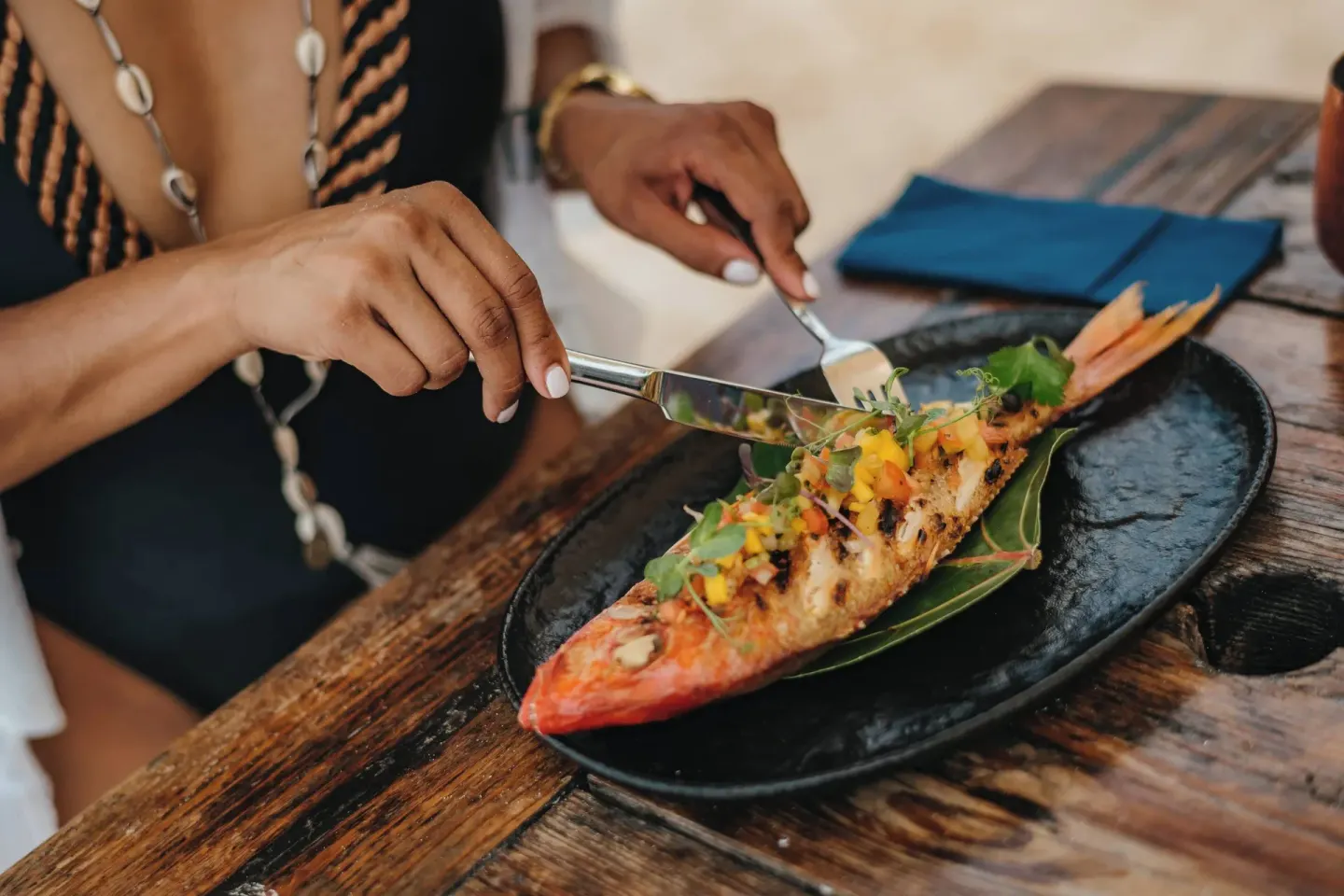 Grilled whole fish served on a rustic table at Renaissance Wind Creek Aruba Resort.