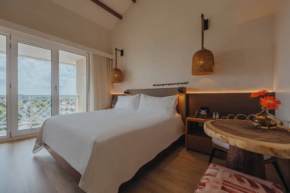 King bed guest room with balcony doors and dining table at Renaissance Wind Creek Aruba Resort.