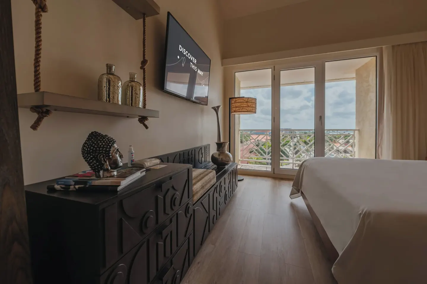 Island view guest room with bed, balcony doors and media console at Renaissance Wind Creek Aruba Resort.