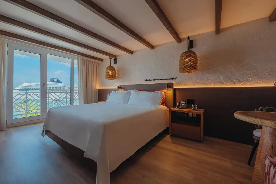 Ocean View room with king bed, balcony doors, and small table at Renaissance Wind Creek Aruba Resort.