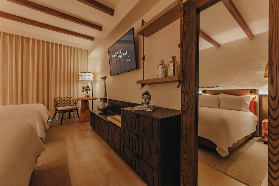 Guest room with bed, TV, mirror, and warm wood accents at Renaissance Wind Creek Aruba Resort.