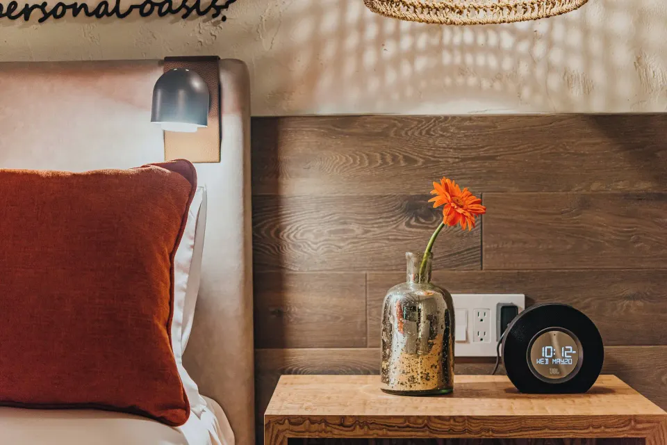 A guest room nightstand with flower, lamp, and clock at Renaissance Wind Creek Aruba Resort.