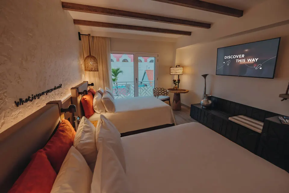 Two-bed guest room with TV and balcony doors at Renaissance Wind Creek Aruba Resort.