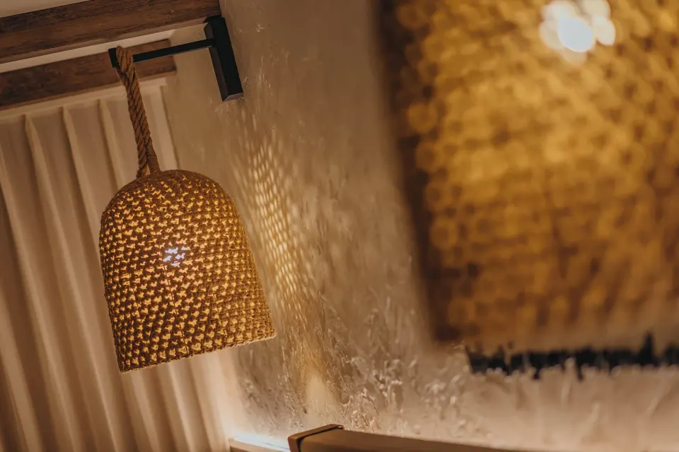 Woven hanging light beside a guest room bed at Renaissance Wind Creek Aruba Resort.