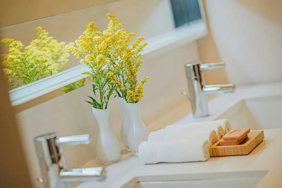 Bathroom vanity with flowers, towels, and soap in a suite at Renaissance Wind Creek Aruba Resort.