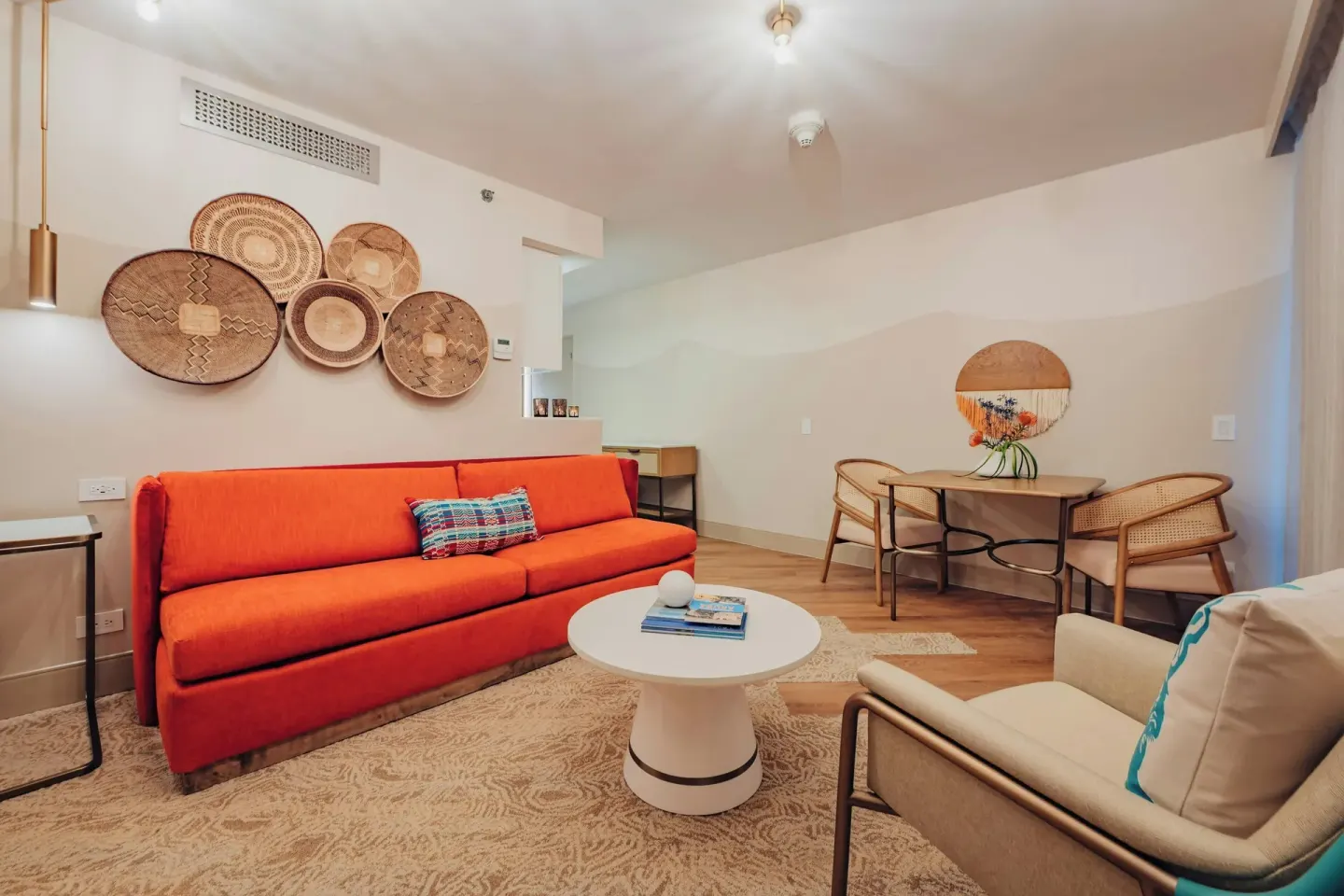 Suite living area with orange sofa and dining table at Renaissance Wind Creek Aruba Resort.