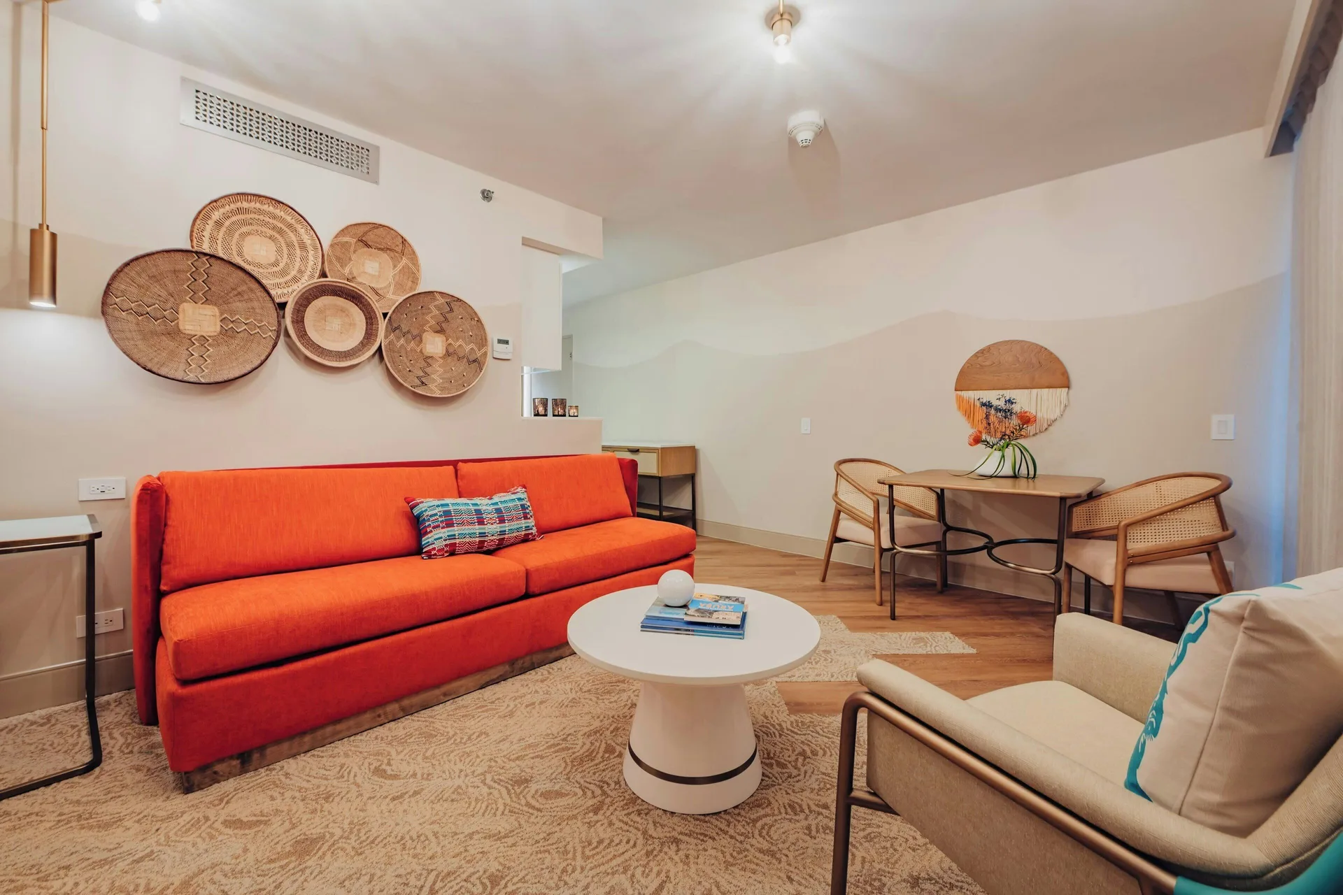 Suite living area with orange sofa and dining table at Renaissance Wind Creek Aruba Resort.