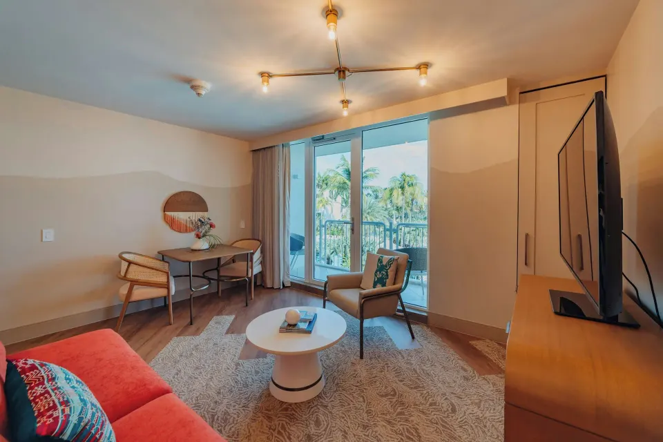 Suite living room with balcony doors and TV at Renaissance Wind Creek Aruba Resort.