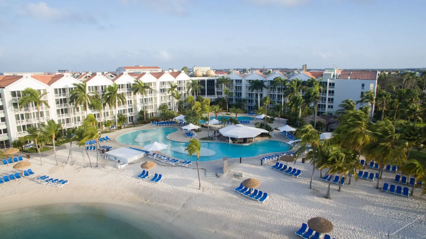 Ocean view from Renaissance Wind Creek Aruba Resort overlooking beach, pools, palms, and resort buildings.