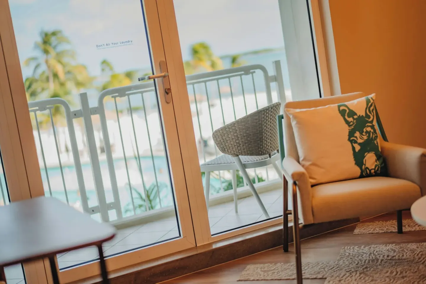 Balcony doors in an ocean view suite at Renaissance Wind Creek Aruba Resort with chair and outdoor seating.