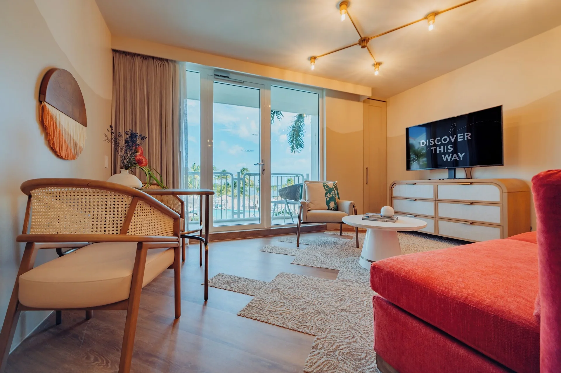 Ocean view one-bedroom suite living area at Renaissance Wind Creek Aruba Resort with balcony doors and seating.