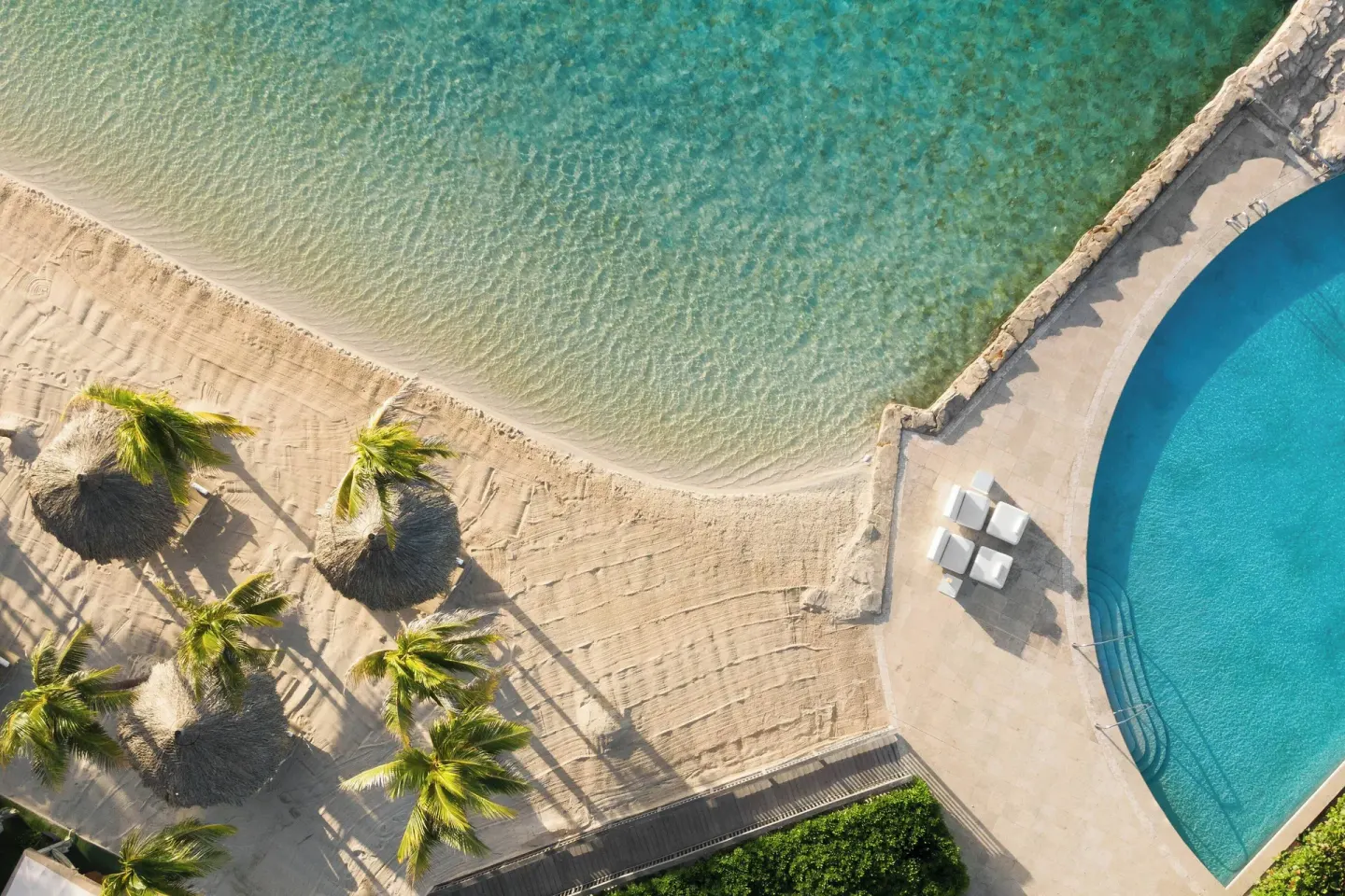 Aerial view of beach, palm trees, and pool at Renaissance Wind Creek Curacao Resort.
