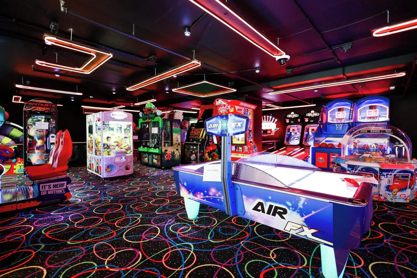 A neon-lit arcade with air hockey and basketball games at Renaissance Wind Creek Curacao Resort.