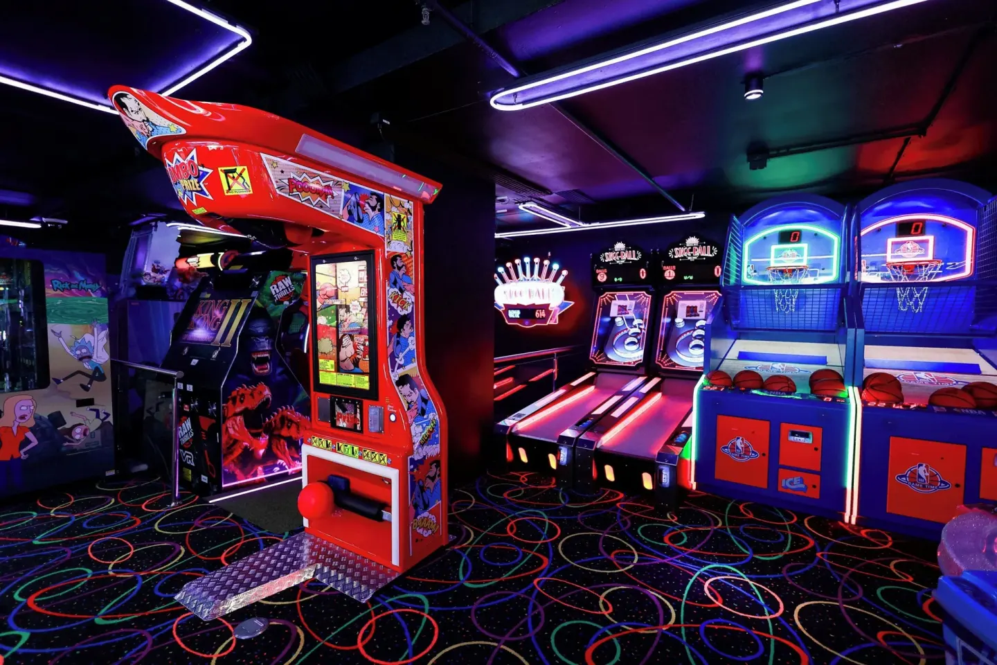 Arcade basketball and game machines glow under neon lights at Renaissance Wind Creek Curacao Resort.