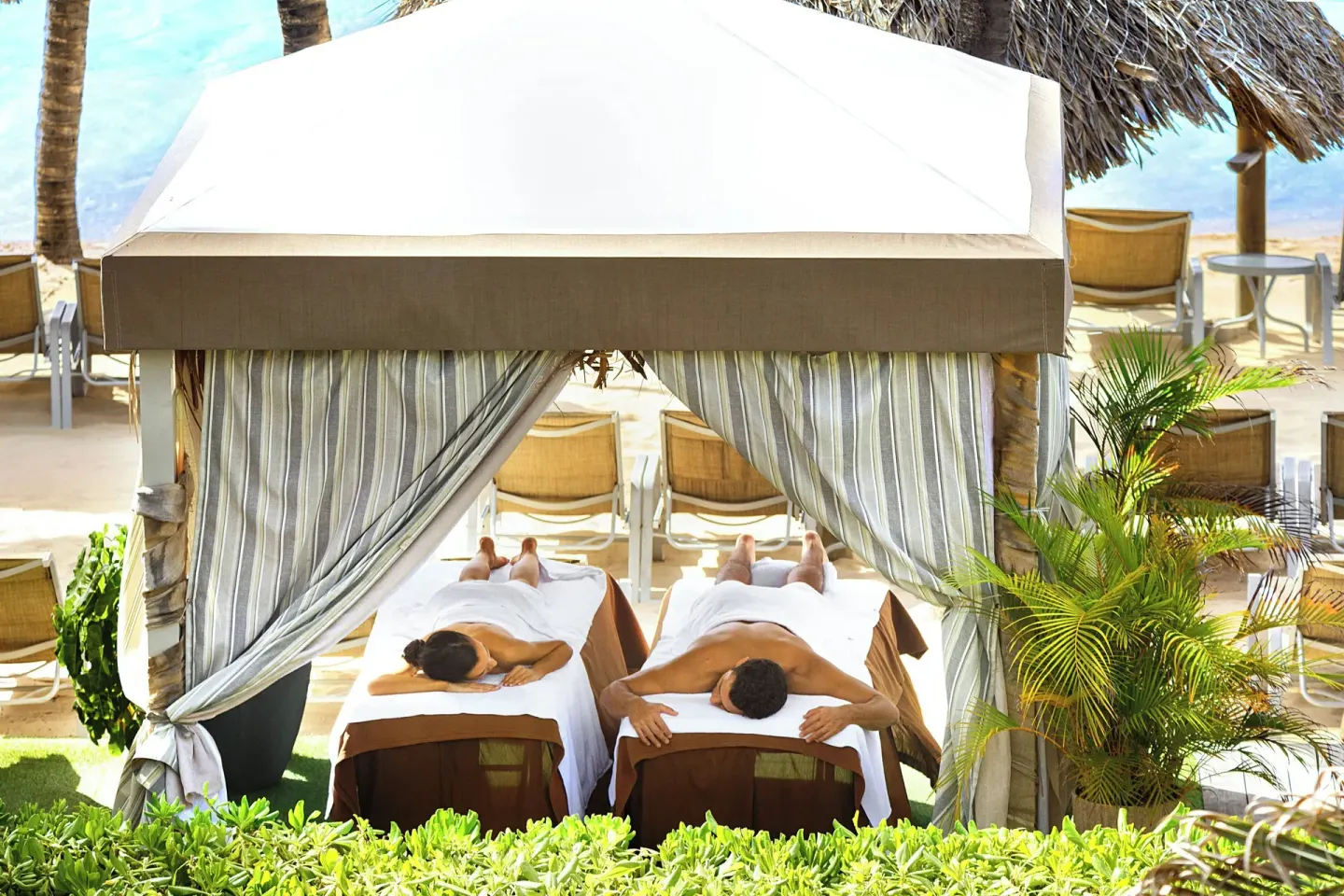 Couple on massage tables in a beach cabana at Renaissance Wind Creek Curacao Resort.