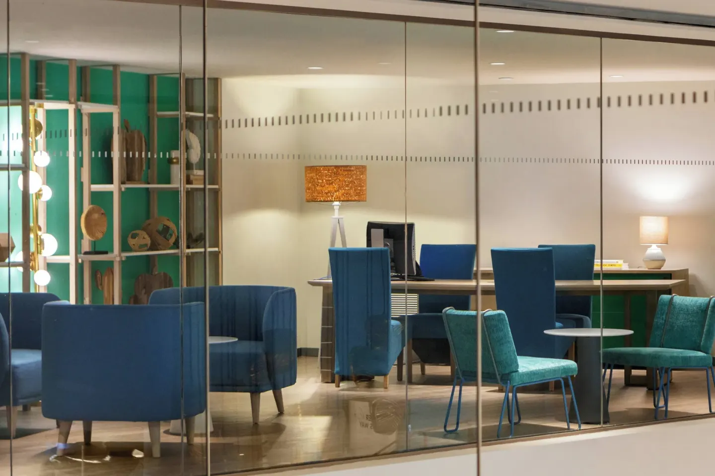 Blue lounge seating and work desks in a glass-walled area at Renaissance Wind Creek Curacao Resort.