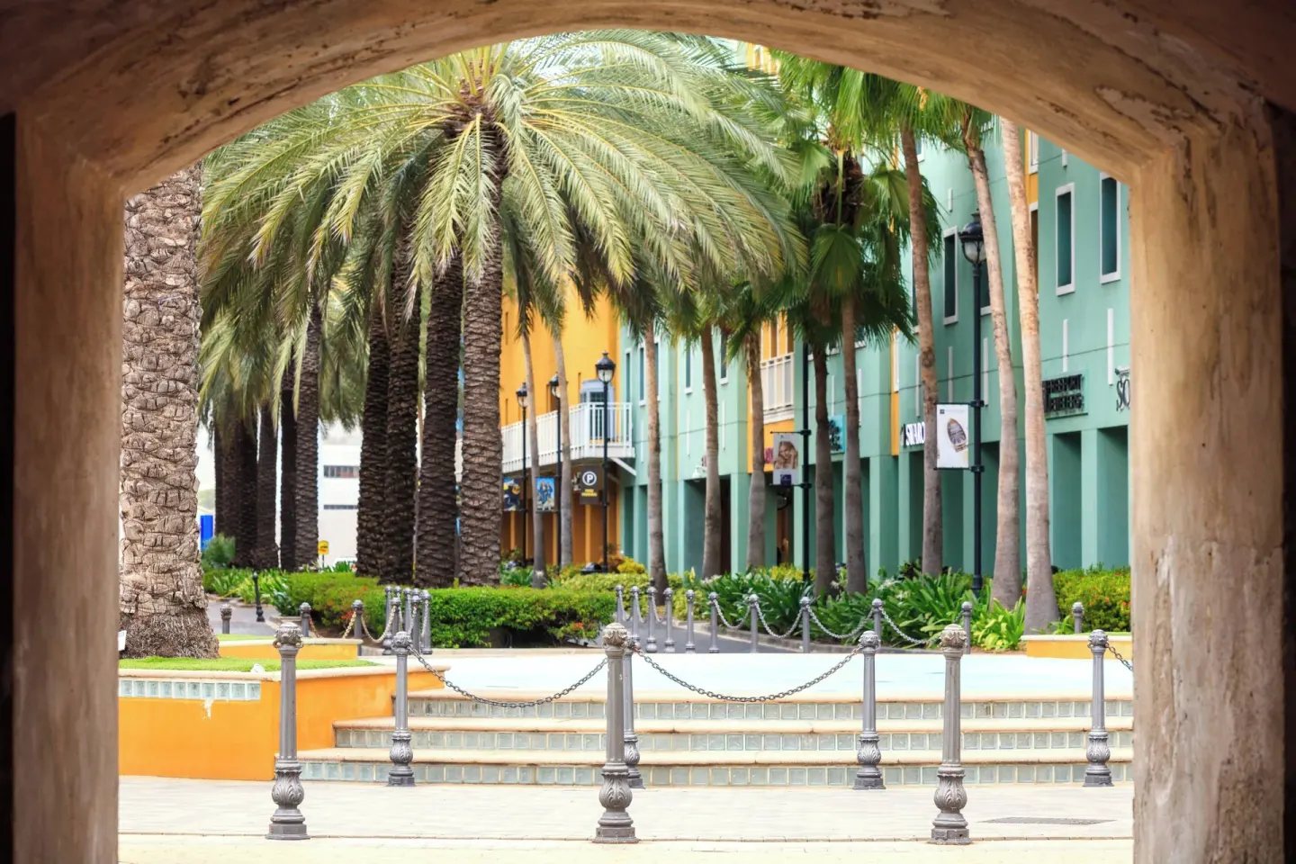 Palm-lined courtyard seen through an arch at Renaissance Wind Creek Curacao Resort.