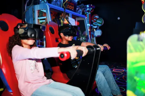 Two children use a virtual reality arcade ride at Renaissance Wind Creek Curacao Resort.