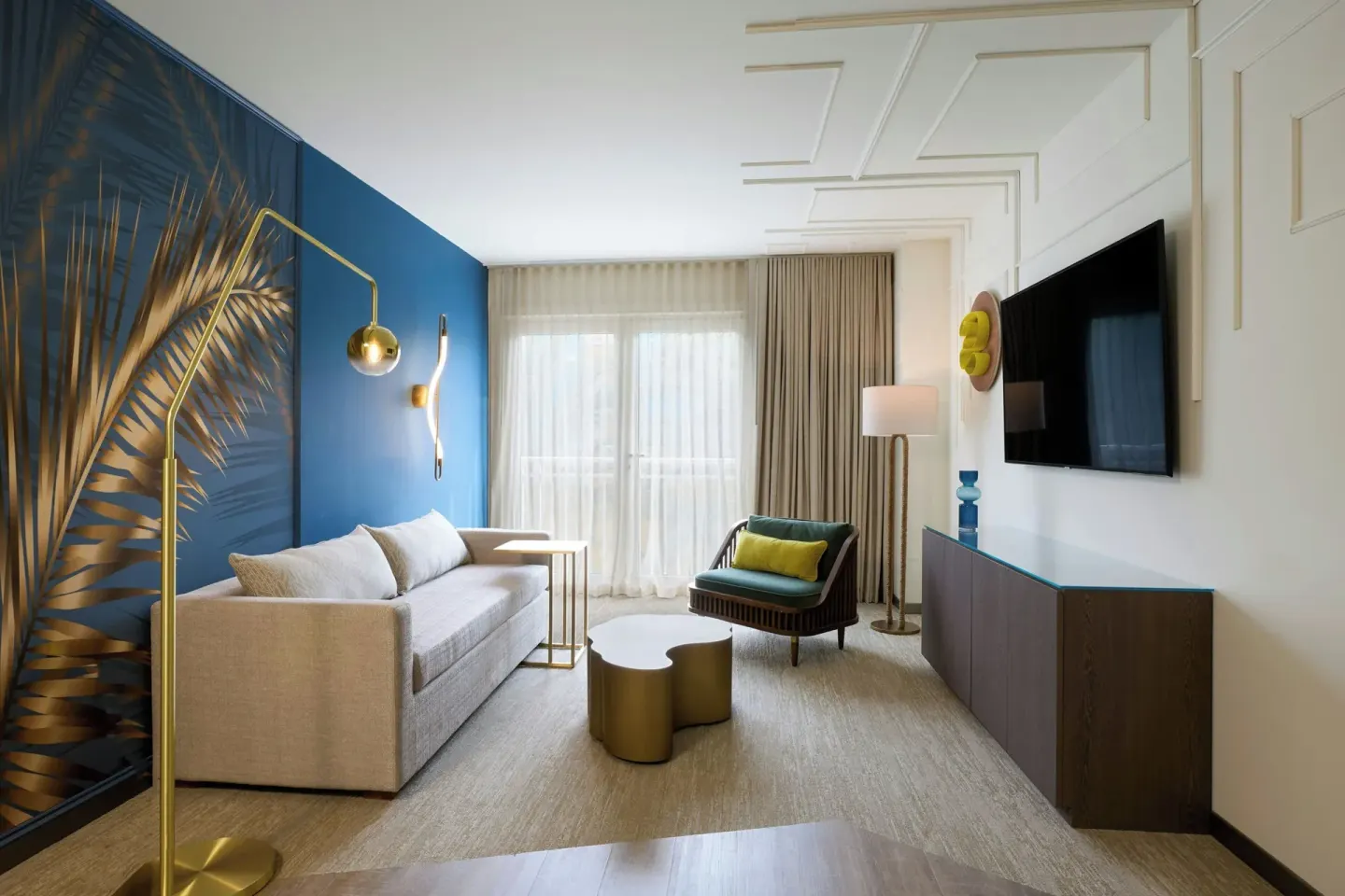 Executive suite living area with sofa, lounge chair and TV at Renaissance Wind Creek Curacao Resort.