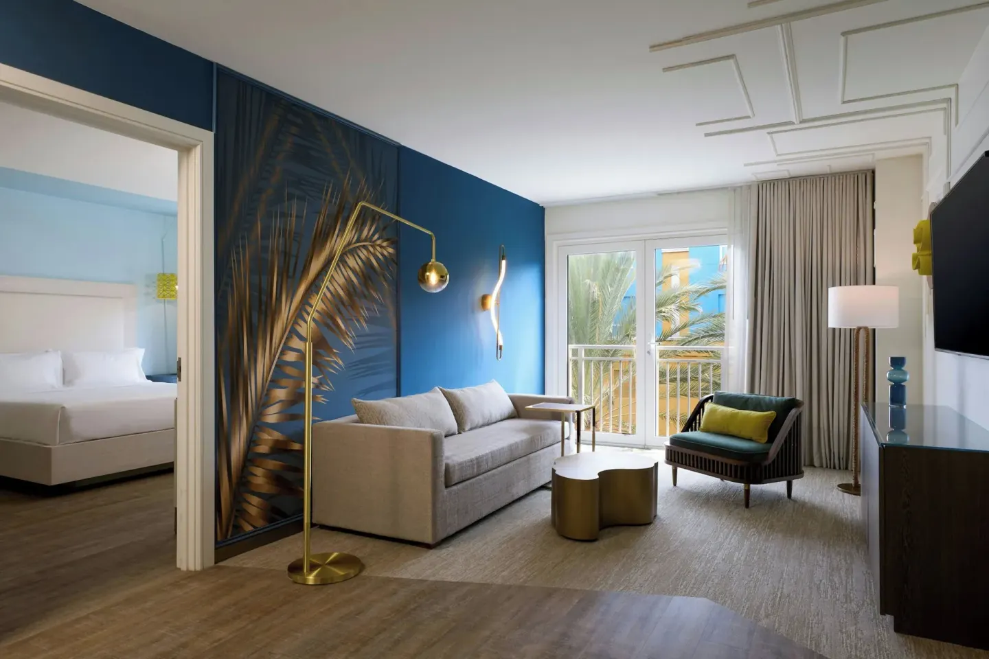 Executive suite living room with balcony doors and bedroom beyond at Renaissance Wind Creek Curacao Resort.