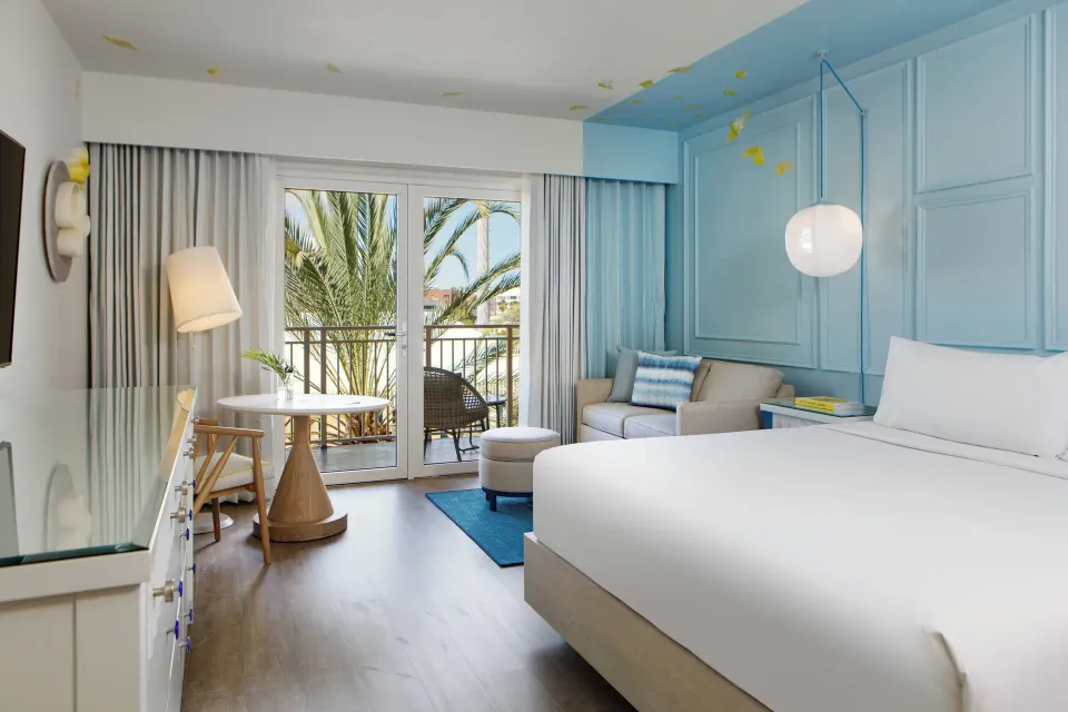 Balcony king room with seating and palm view at Renaissance Wind Creek Curacao Resort.