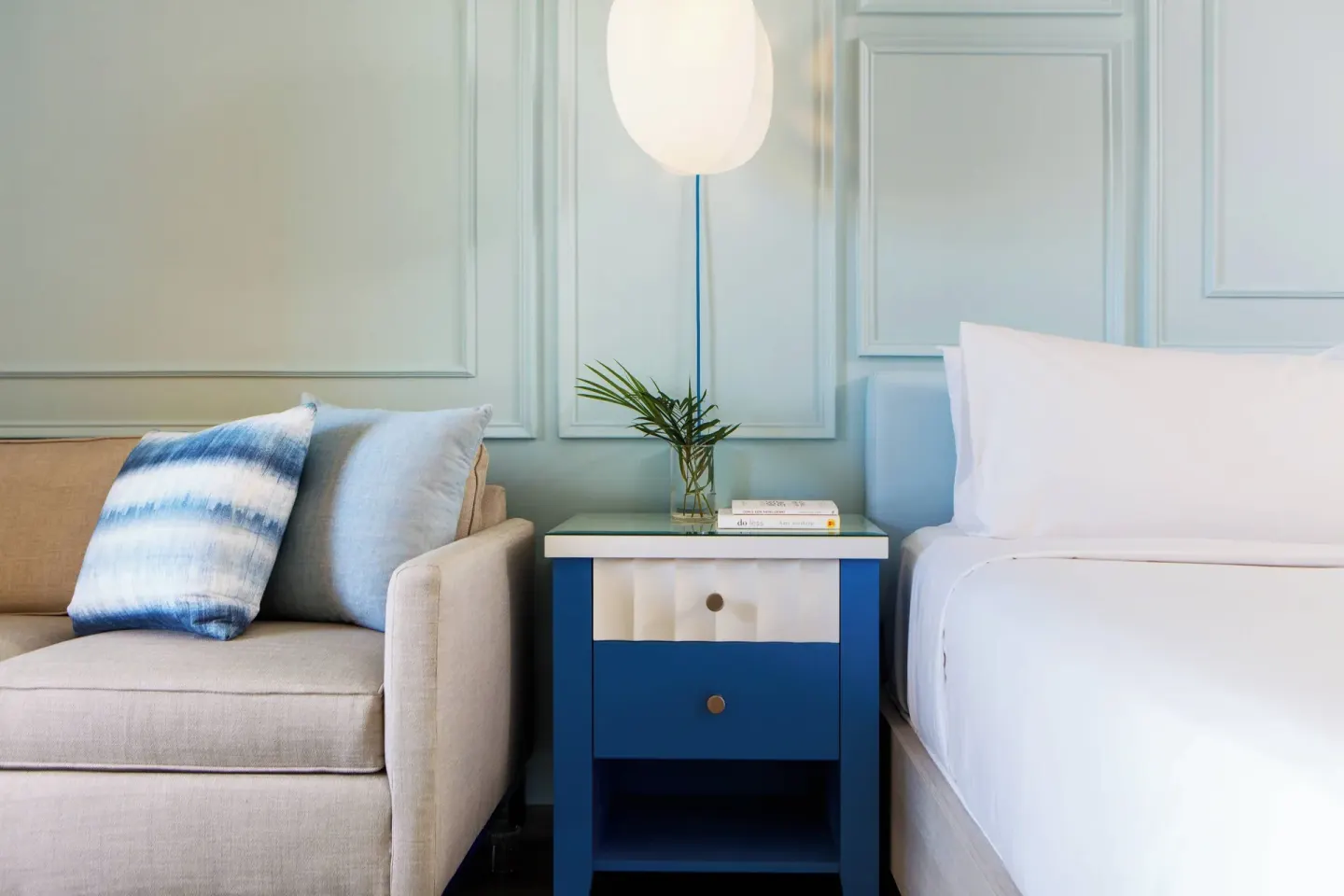 Guest room sofa beside a bed and blue nightstand at Renaissance Wind Creek Curacao Resort.