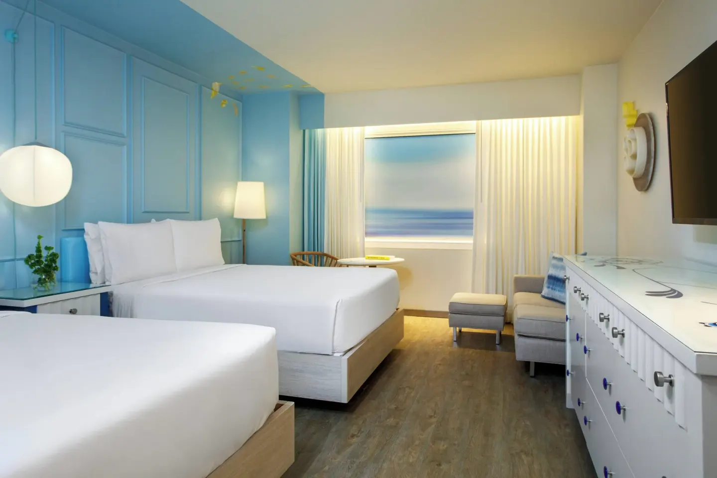 Two-bed guest room with dresser and wall-mounted TV at Renaissance Wind Creek Curacao Resort.