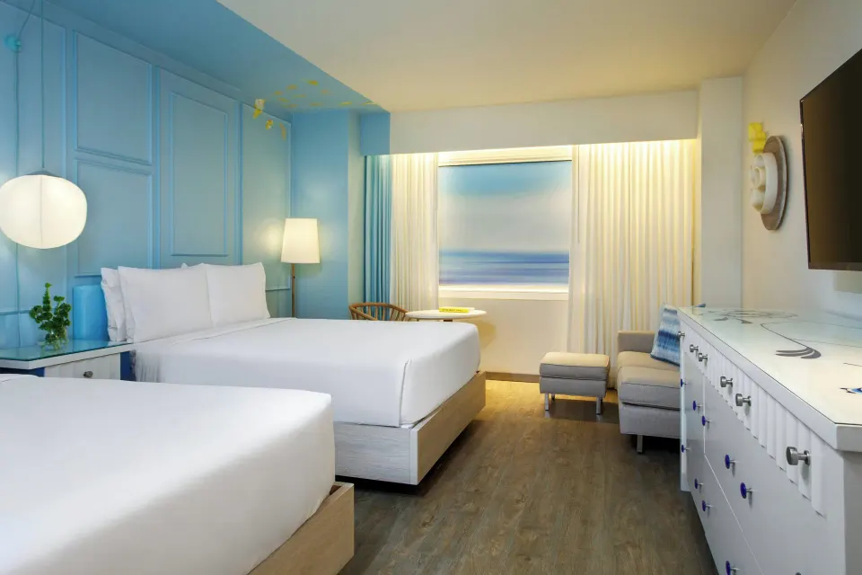 Two-bed guest room with dresser and wall-mounted TV at Renaissance Wind Creek Curacao Resort.