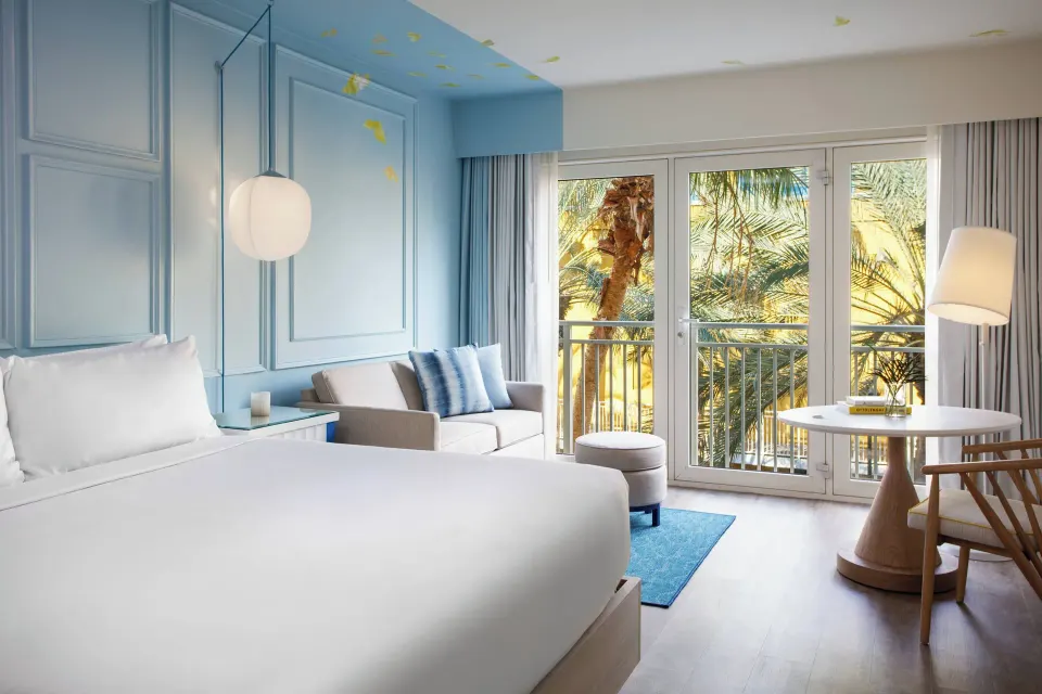King room with sofa, table, and palm-facing doors at Renaissance Wind Creek Curacao Resort.