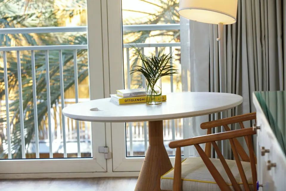 Room table by balcony doors with palm view at Renaissance Wind Creek Curacao Resort.
