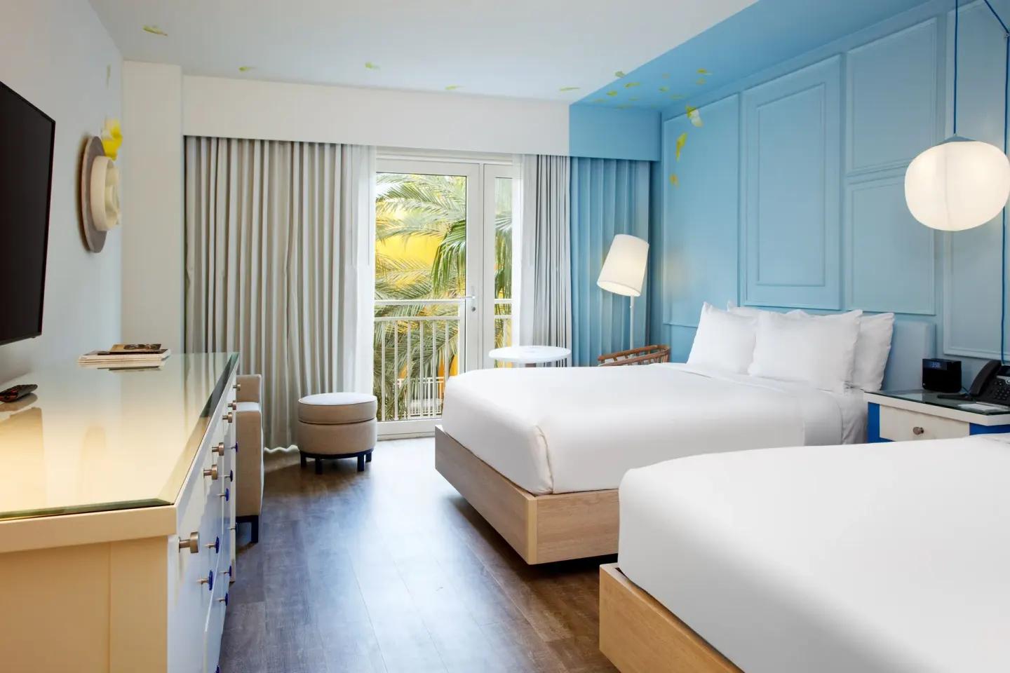 Two-bed guest room with TV and balcony doors at Renaissance Wind Creek Curacao Resort.