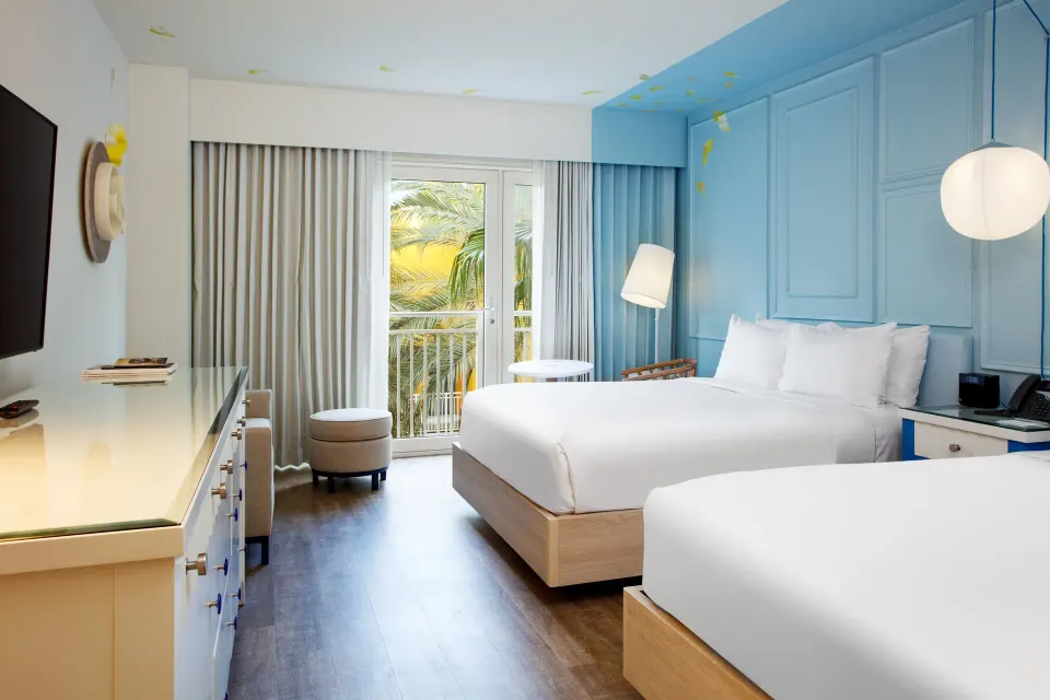 Two-bed guest room with TV and balcony doors at Renaissance Wind Creek Curacao Resort.