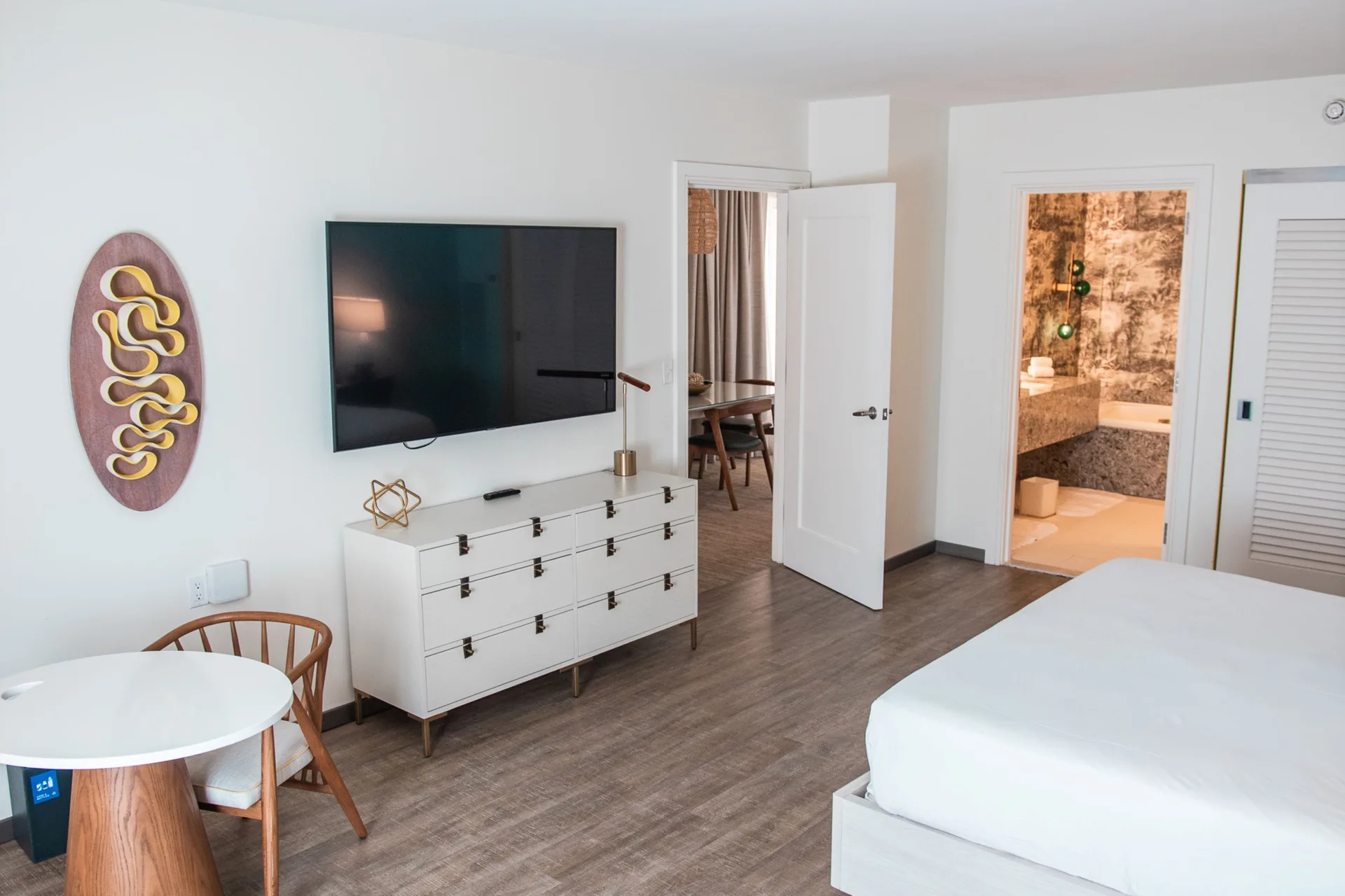 One bedroom suite with bed, TV, dresser and bathroom at Renaissance Wind Creek Curacao Resort.