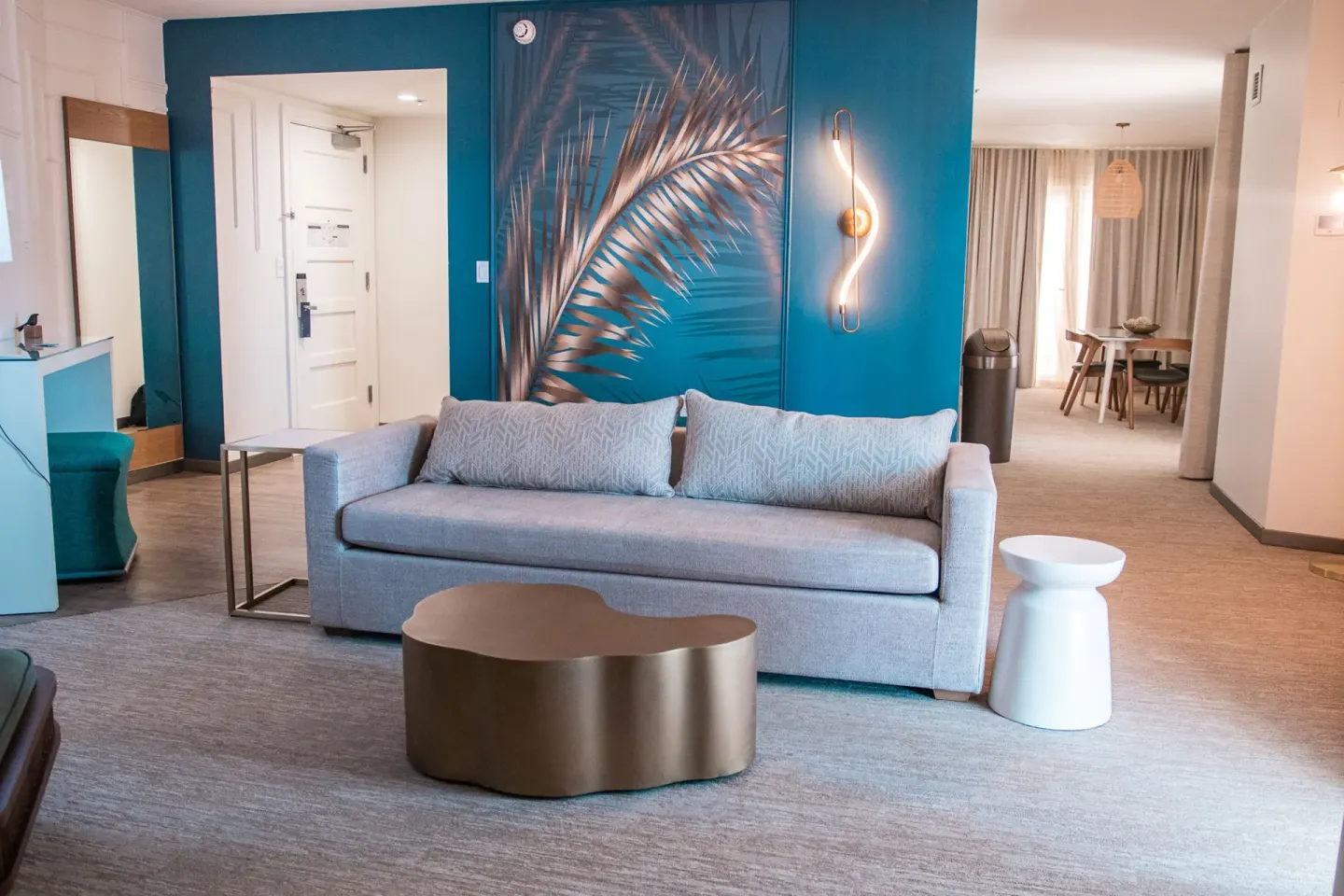 One bedroom suite sitting area with sofa and palm mural at Renaissance Wind Creek Curacao Resort.