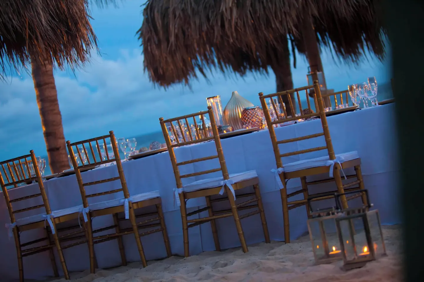 Beach event table with gold chairs and lanterns at Renaissance Wind Creek Curacao Resort.