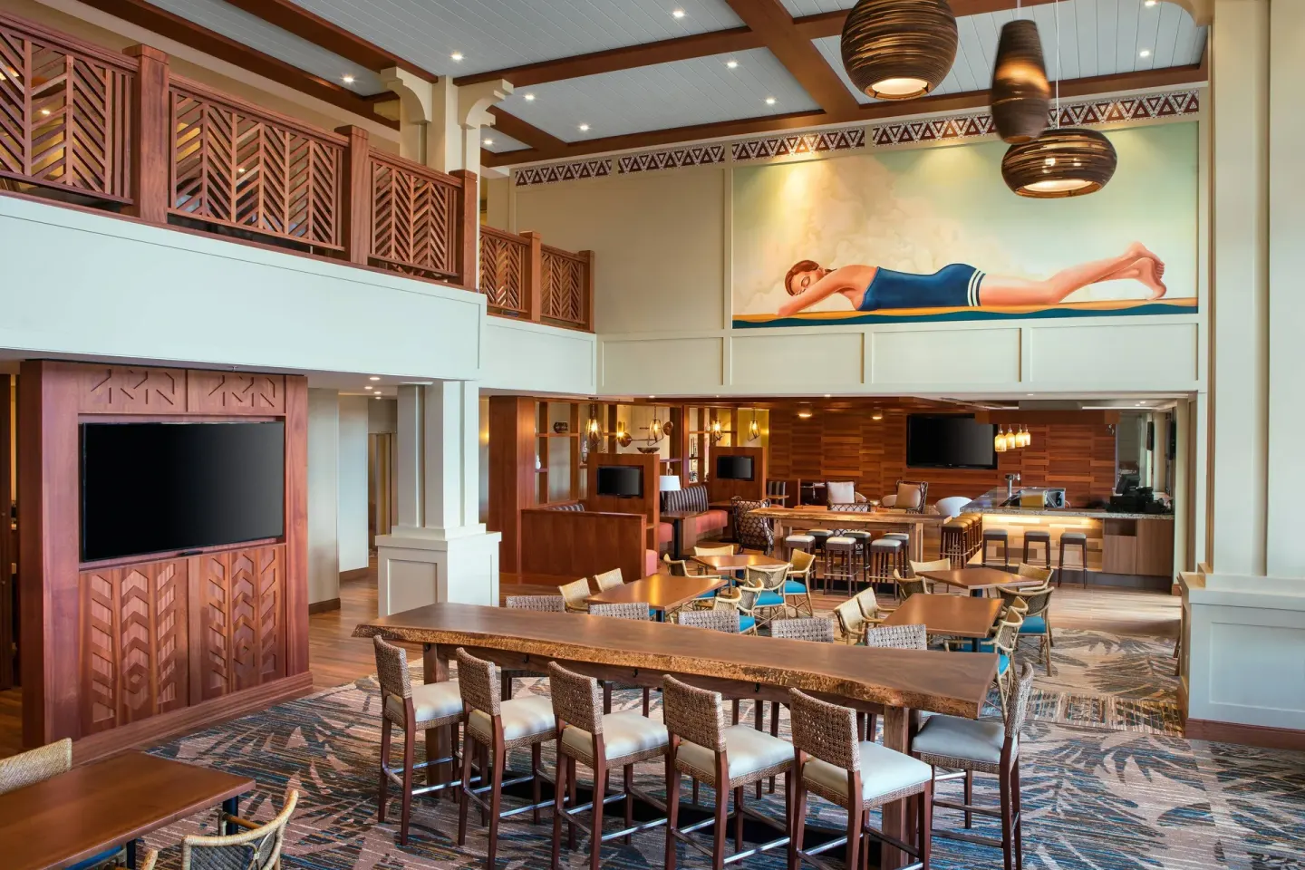 Two-story lobby lounge with tables and wall art at Residence Inn Maui Wailea.