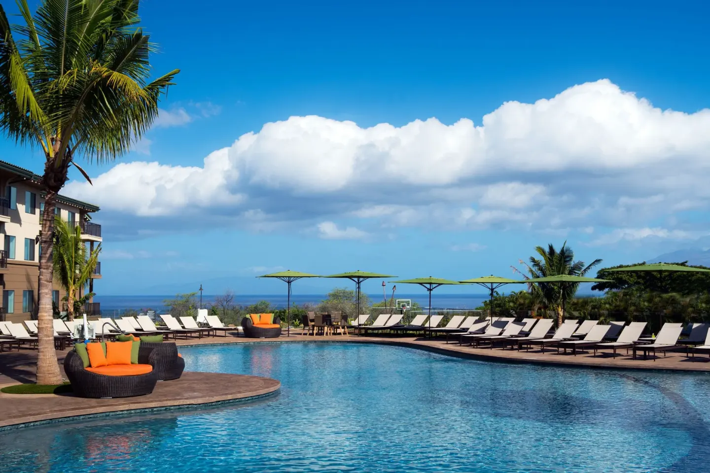 Outdoor pool with loungers and palm trees at Residence Inn Maui Wailea.